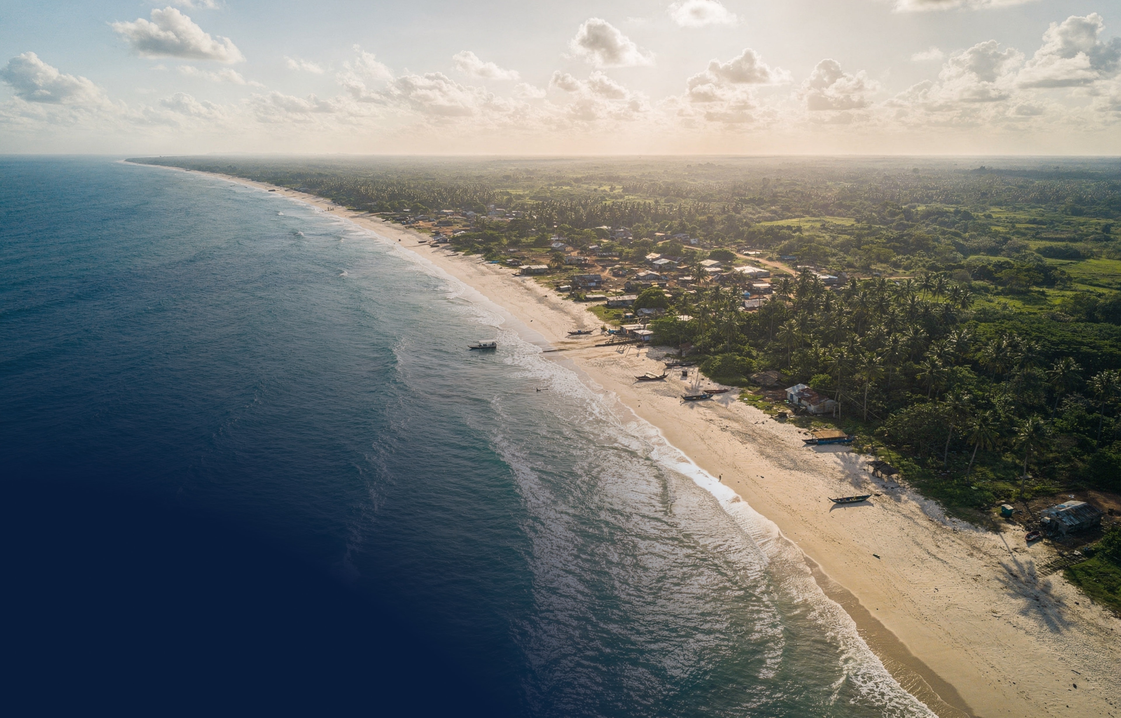 Aerial view of Ghana's southwestern coastline — turquoise Atlantic shallows meeting a palm-lined shore
